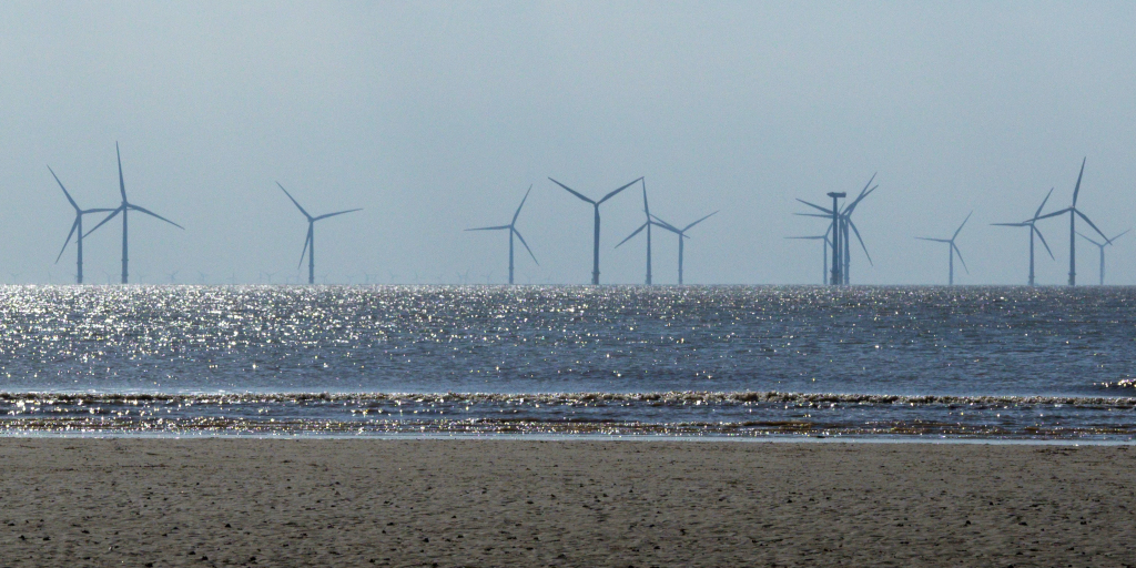 Men Who Stand in Oceans. Photo by Brett Jordan on Unsplash_Shows wind turbines at Crosby Beach, UK